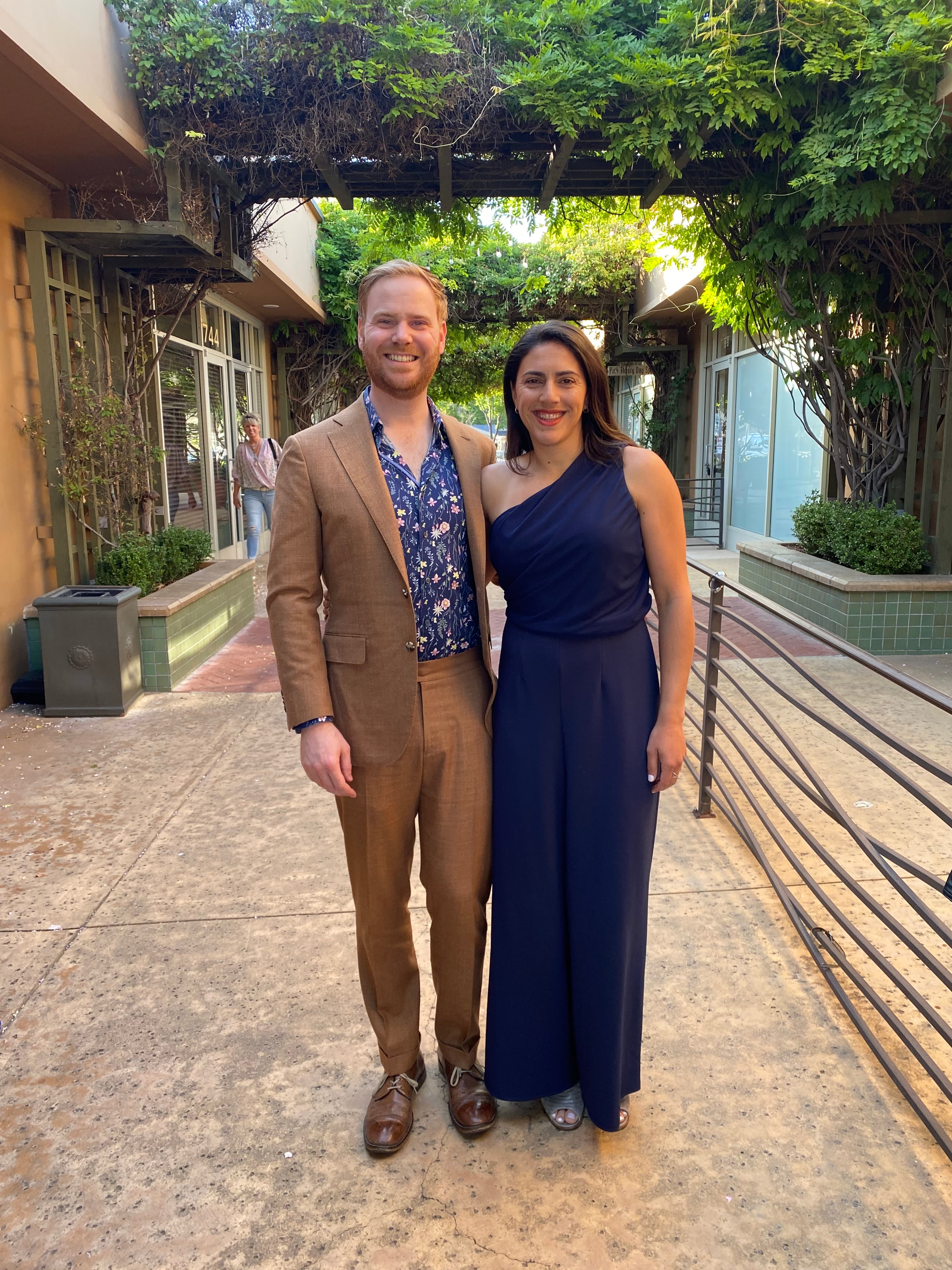 Ariana and Erik posing for a picture in front of a trellis covered in vines