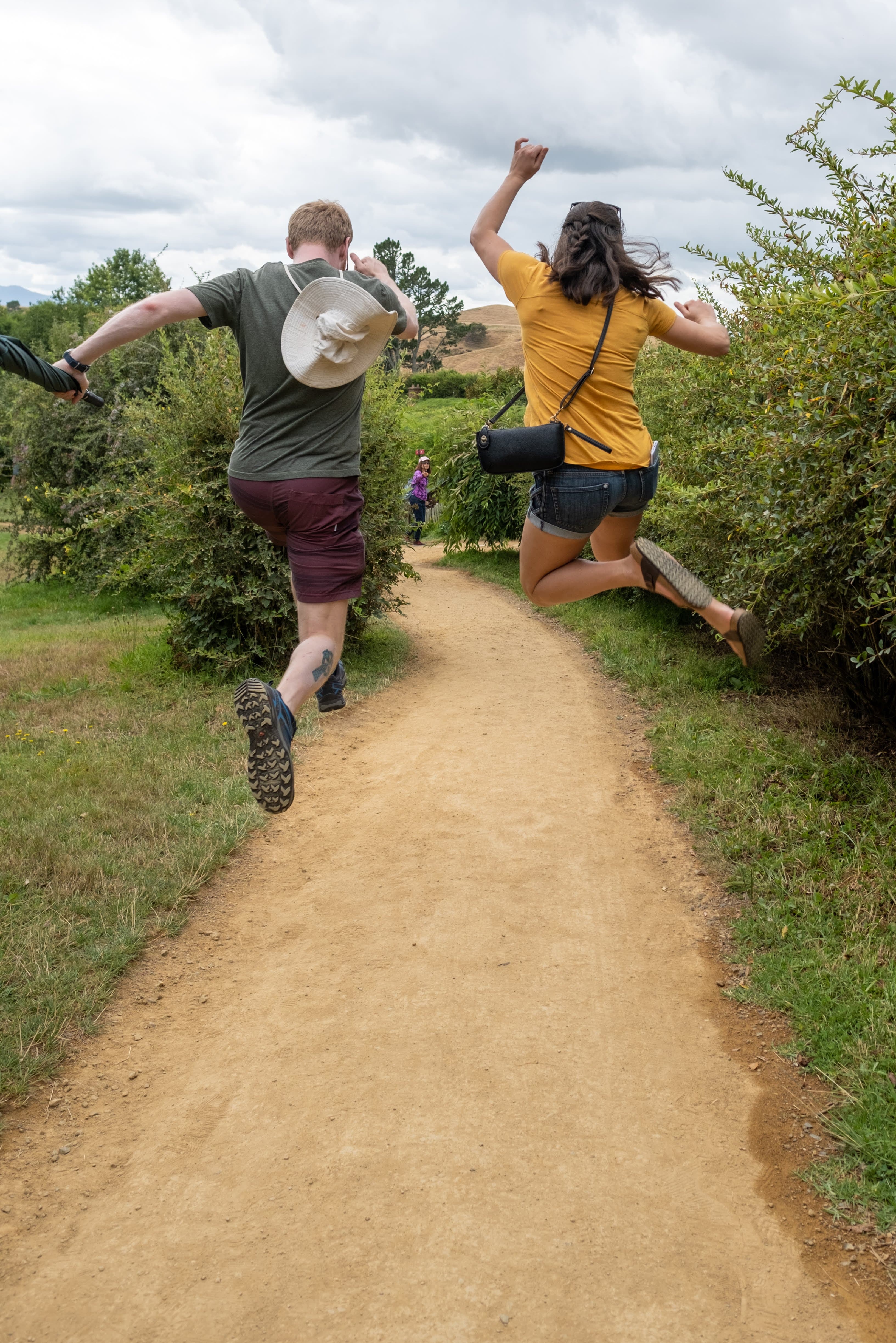 Ariana and Erik skipping along a path in Hobbiton, Matamata, New Zealand