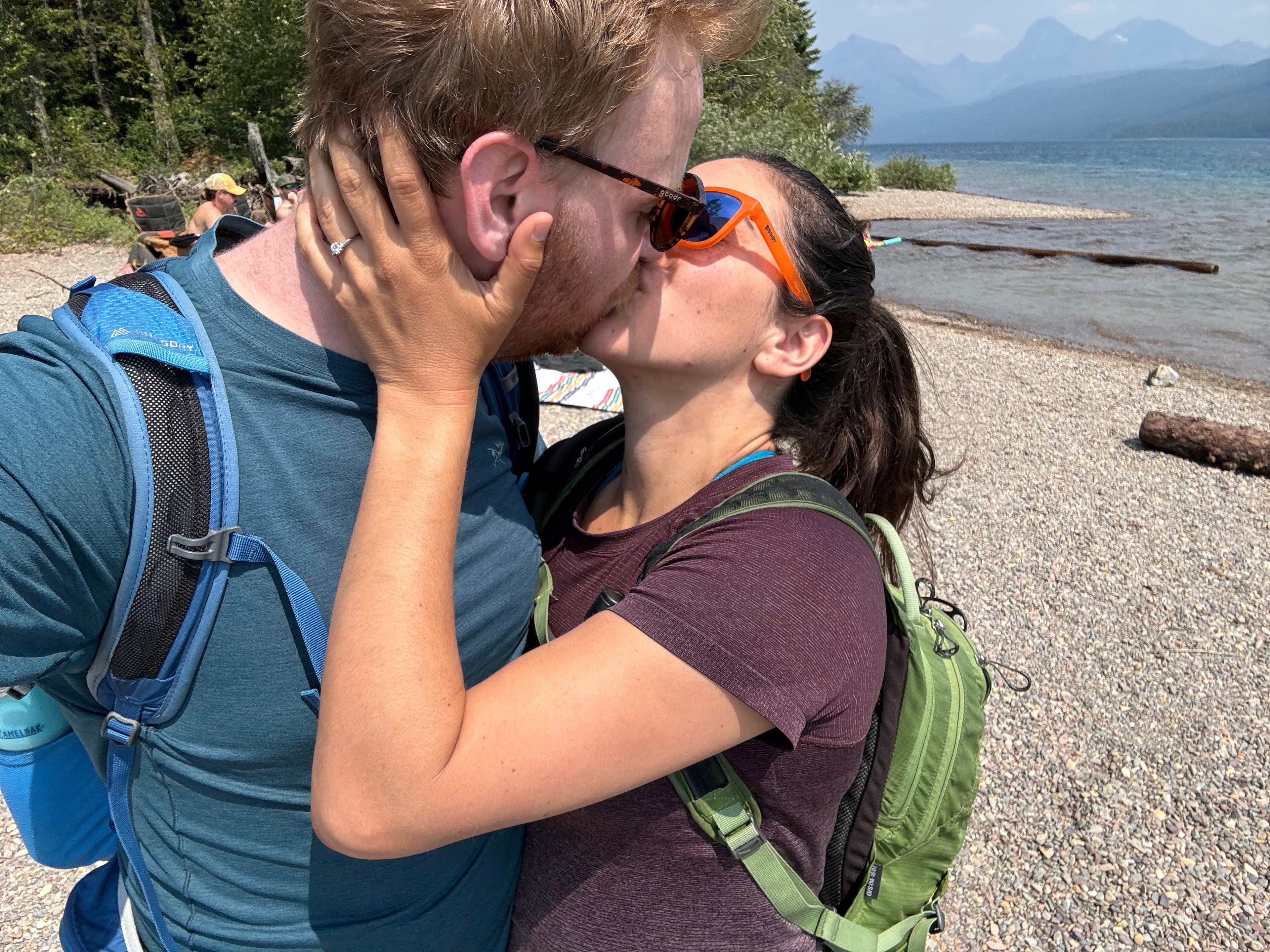 Erik and Ariana kissing on a beach in Glacier National Park, Montana, after just getting engaged