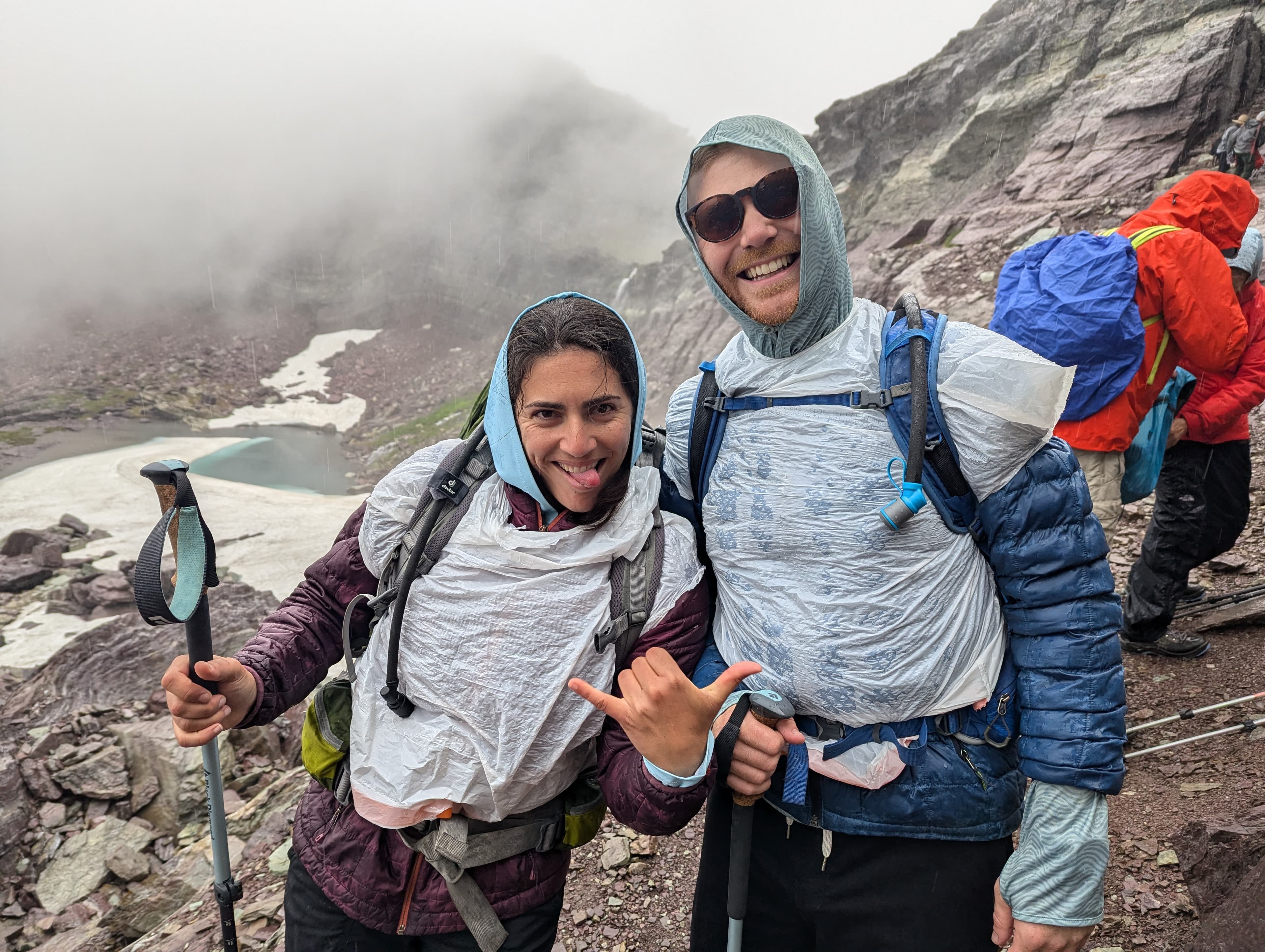 Ariana and Erik hiking in the rain in Glacier National Park, Montana using trash bags as rain ponchos