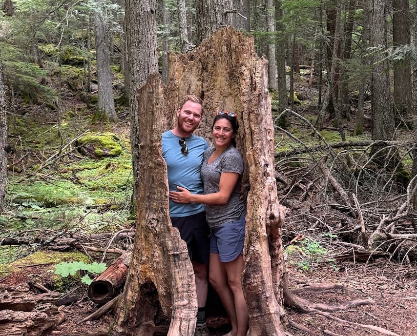 Erik and Ariana posing in a hollow tree in Glacier National Park, Montana