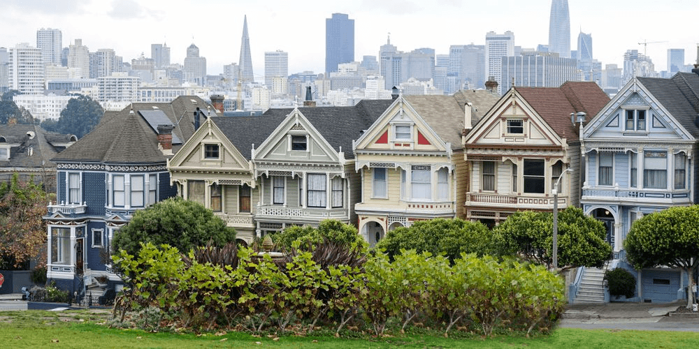 The Painted Ladies, a famous row of colorful Victorian houses in San Francisco, with the city skyline in the background