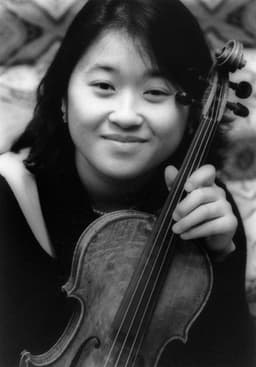 Michelle holding her violin, smiling at the camera.