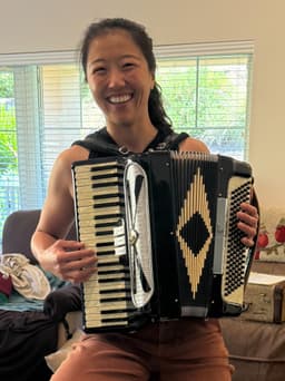 Julie holding her accordion, smiling at the camera.